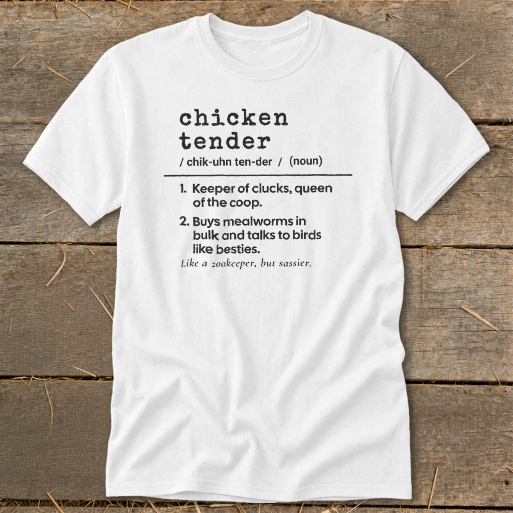 A white t-shirt featuring humorous dictionary-style text defining chicken tender on a rustic wooden background.
