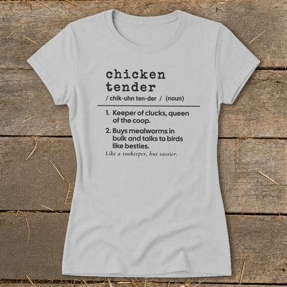 Light gray women's t-shirt printed with a humorous definition of a chicken tender on a rustic wooden background.