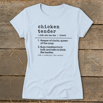 A light blue t-shirt with black dictionary-style text defining chicken tender on a rustic wooden background.