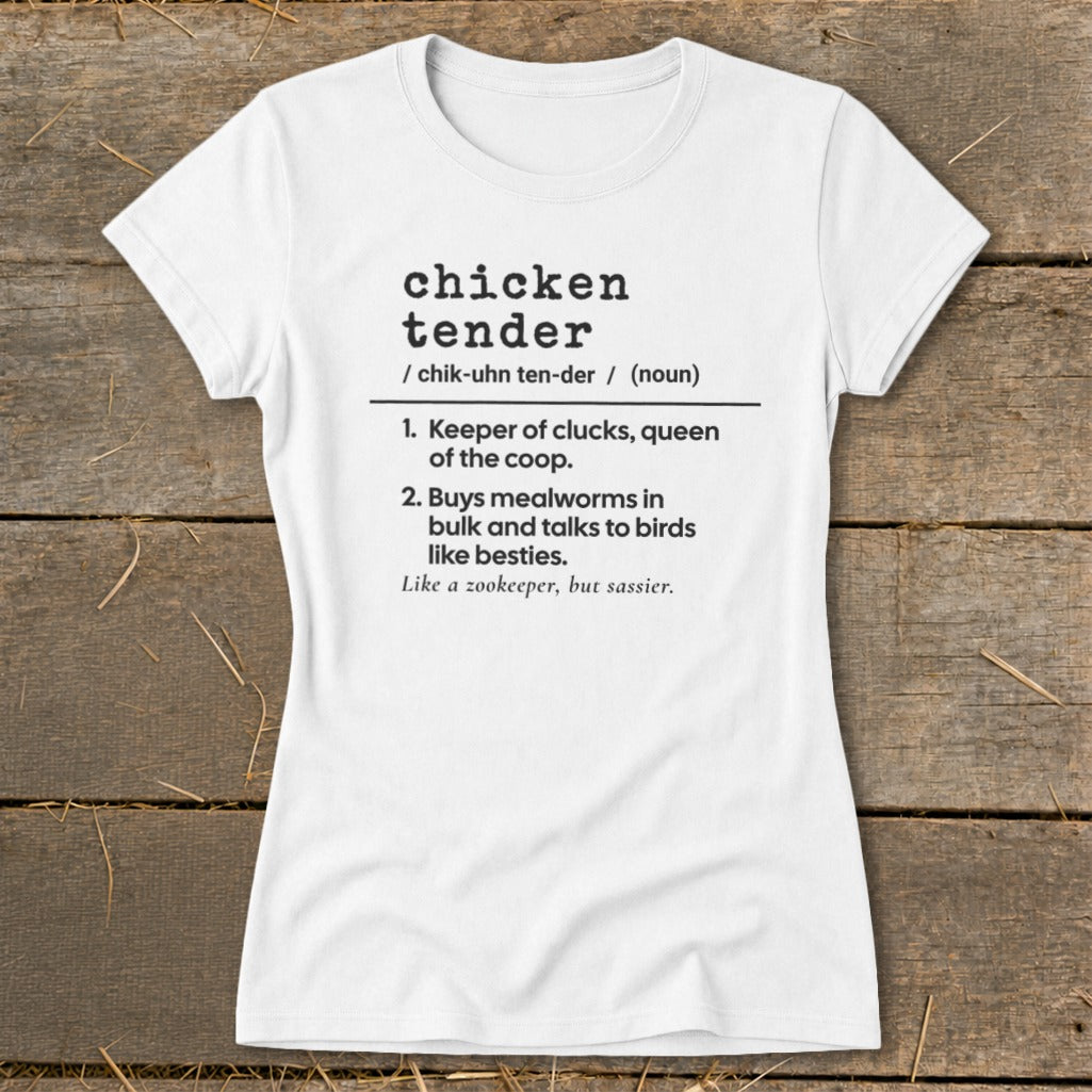 A white short-sleeved t-shirt printed with humorous dictionary definition text about chicken tenders on a wooden background.