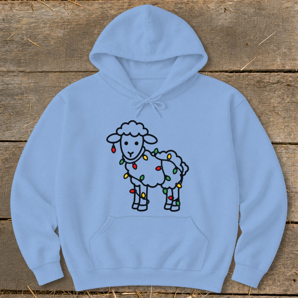 Light blue hooded sweatshirt featuring a cartoon sheep wrapped in colorful holiday lights on a wooden surface.