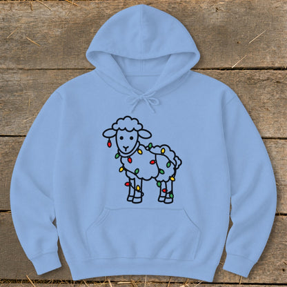 Light blue hooded sweatshirt featuring a cartoon sheep wrapped in colorful holiday lights on a wooden surface.