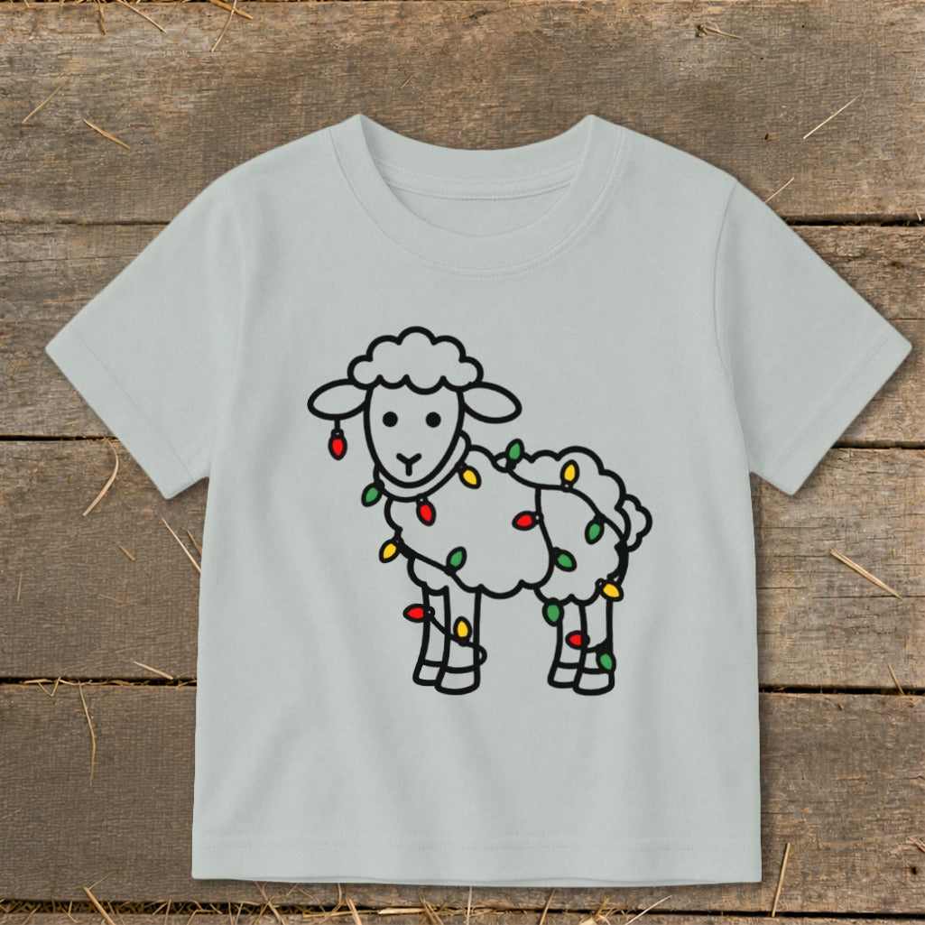 Light gray children's t-shirt featuring a cartoon sheep tangled in colorful holiday lights.