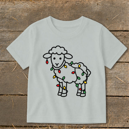 Light gray children's t-shirt featuring a cartoon sheep tangled in colorful holiday lights.