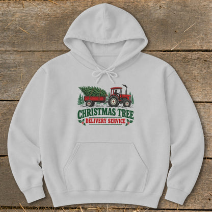 White hoodie with a "Christmas Tree Delivery Service" graphic featuring a red tractor and trailer.