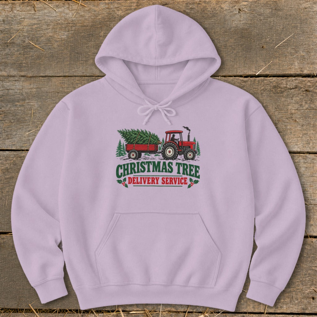 Pink hoodie with a graphic of a red tractor towing a Christmas tree with "Christmas Tree Delivery Service" text.