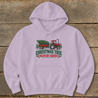 Pink hoodie with a graphic of a red tractor towing a Christmas tree with "Christmas Tree Delivery Service" text.