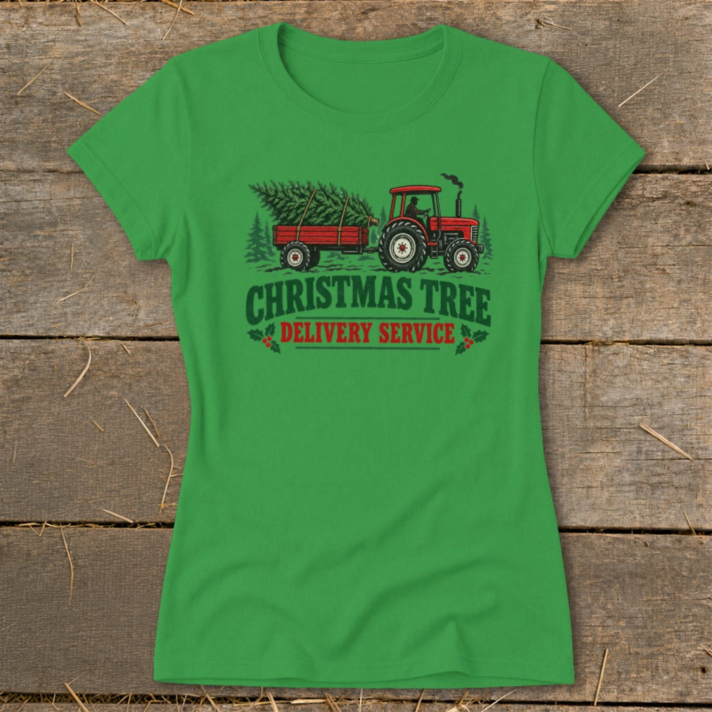 Green t-shirt graphic of a red tractor pulling a trailer with Christmas trees, text reads "Christmas Tree Delivery Service".