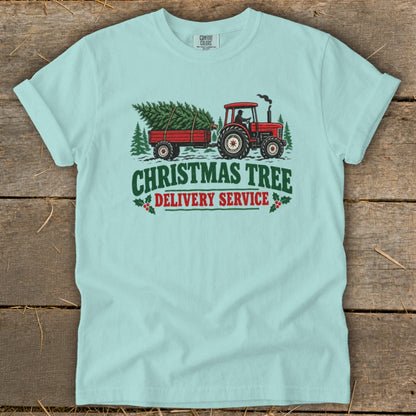 Light blue t-shirt with red tractor, trailer, and Christmas tree graphic and text.
