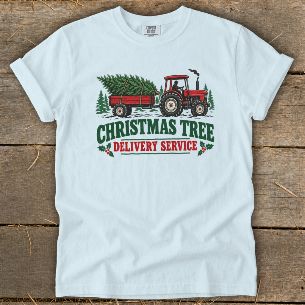 White t-shirt with graphic of red tractor towing Christmas tree in trailer.