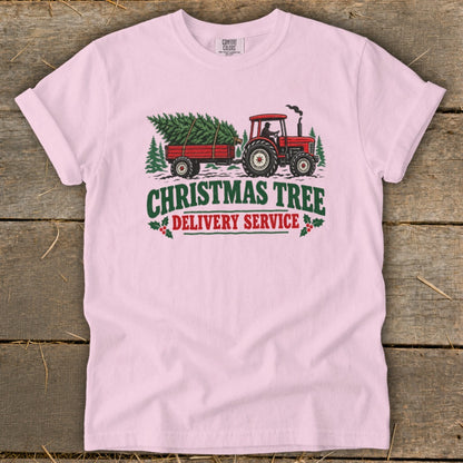 Pink t-shirt with graphic of red tractor pulling Christmas tree delivery trailer.