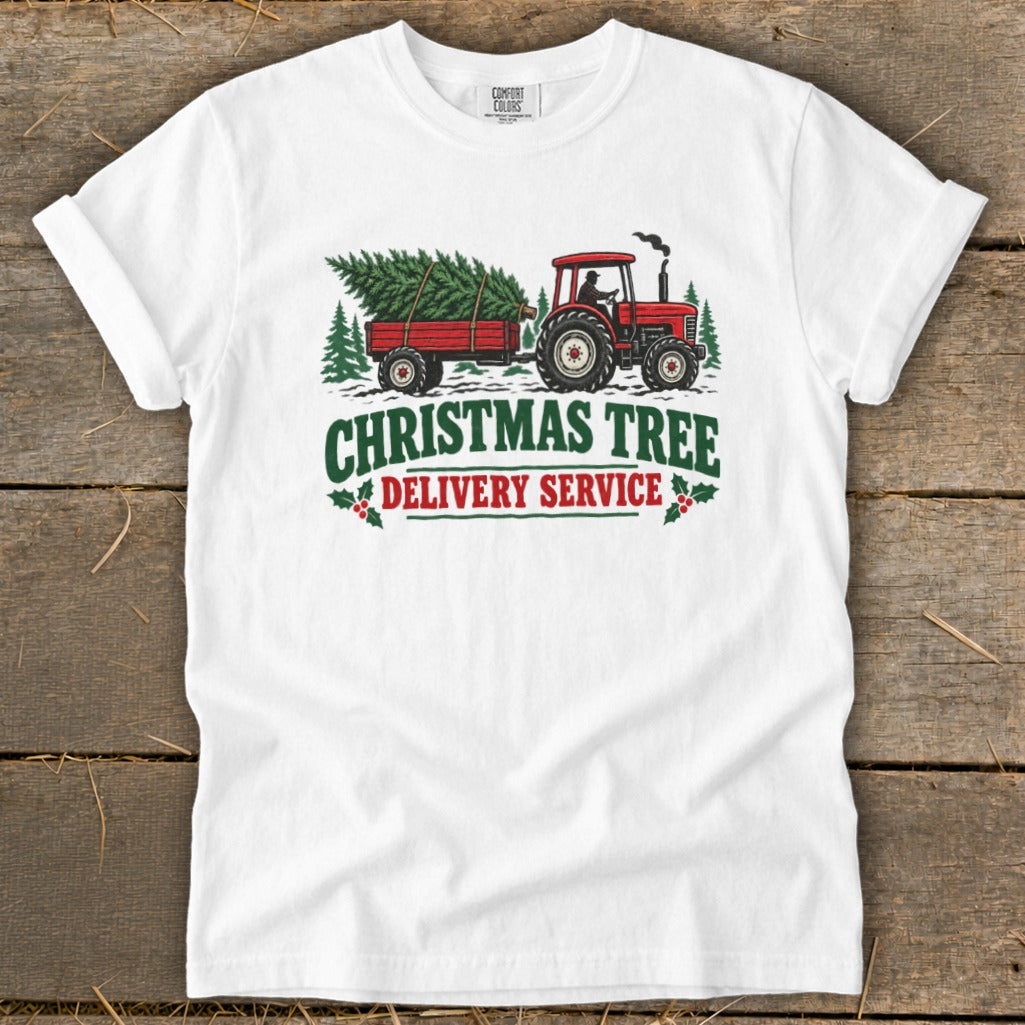 White t-shirt with red tractor pulling Christmas tree, text "Christmas Tree Delivery Service".