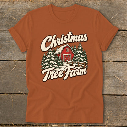 Orange t-shirt with "Christmas Tree Farm" text over a snowy barn and pine trees.