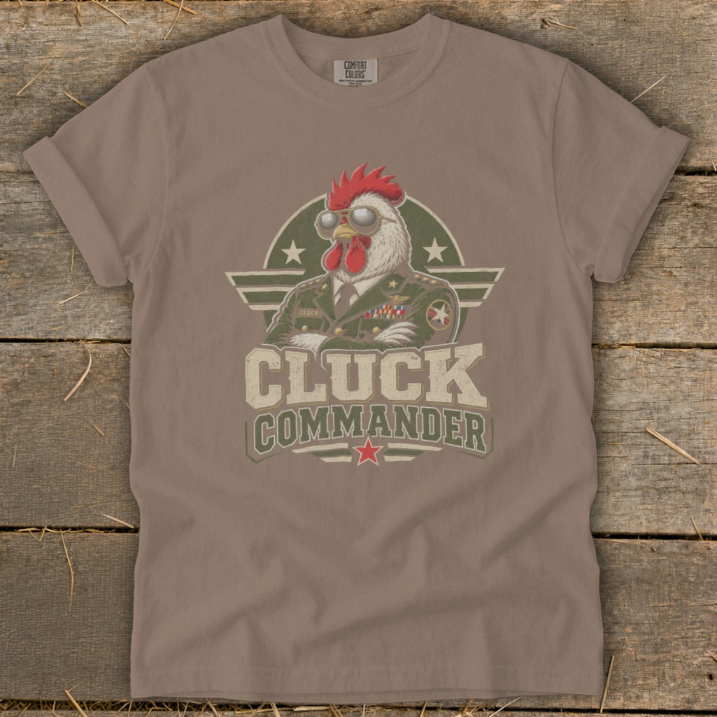A brown short-sleeve t-shirt with a graphic of a chicken wearing a military uniform and sunglasses, with the text Cluck Commander.