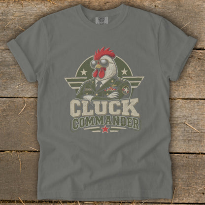 A grey t-shirt featuring a graphic of a rooster in a military uniform wearing sunglasses, with the text Cluck Commander.