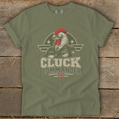An olive green t-shirt featuring a graphic of a rooster in a military uniform with sunglasses and the text Cluck Commander.