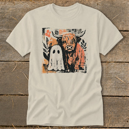 Highland cow and ghost illustration with floral accents on a light t-shirt.
