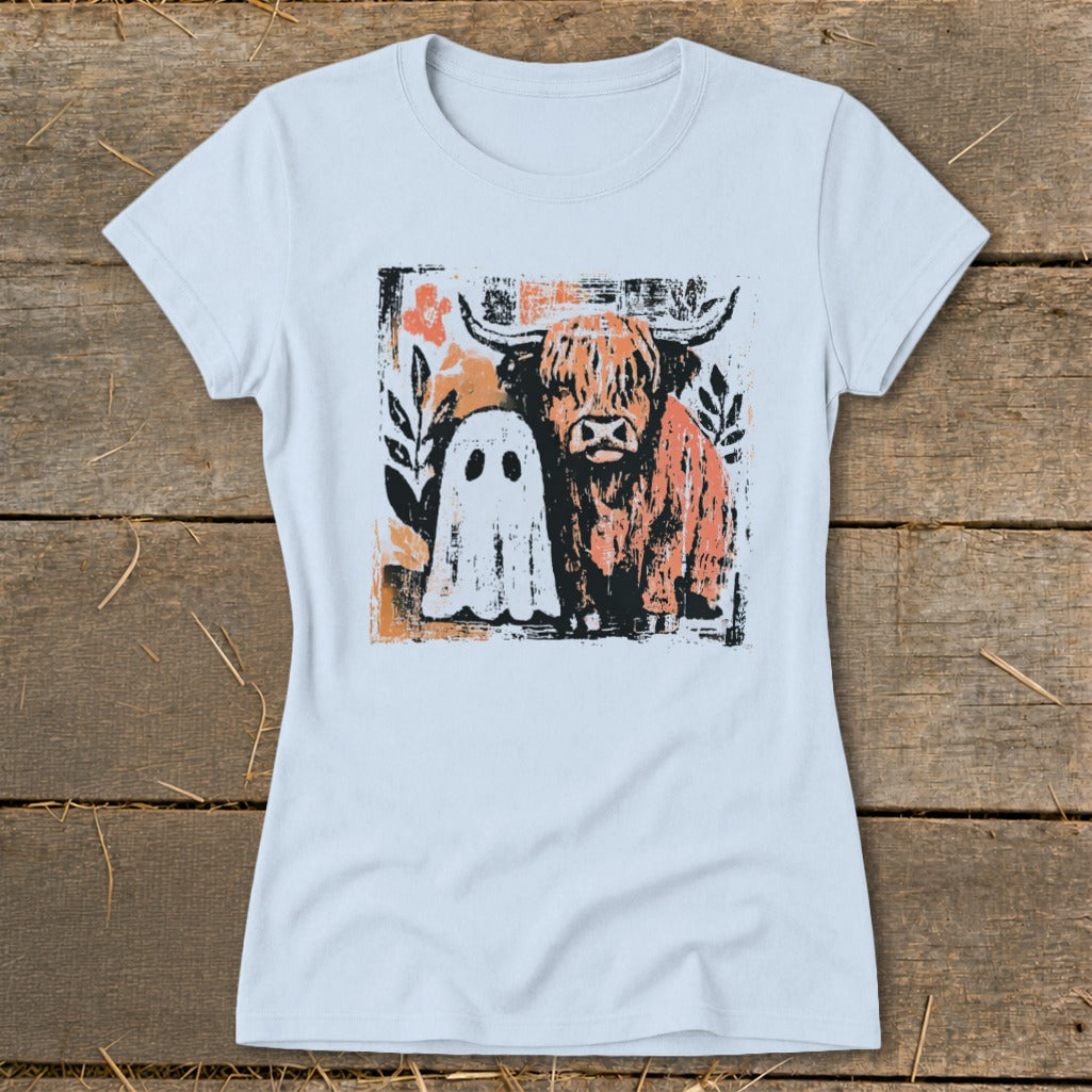 Highland cow and ghost graphic with floral accents on a light blue t-shirt.