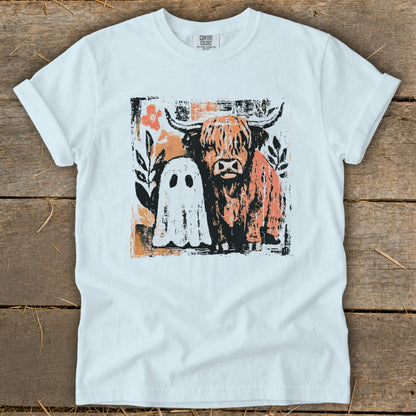 White t-shirt with graphic of Highland cow and ghost, with floral accents.