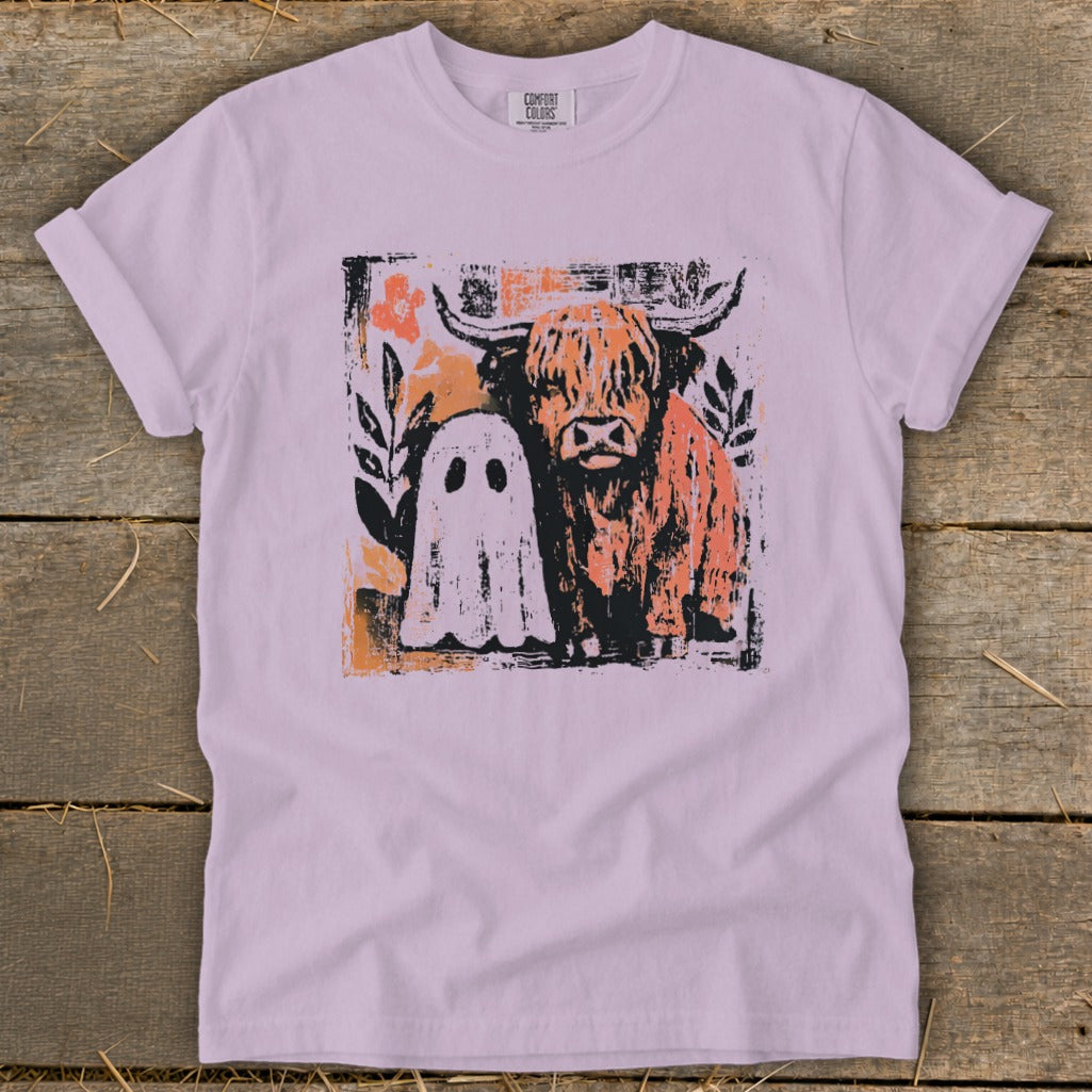 Highland cow and ghost graphic on a purple t-shirt with floral accents.