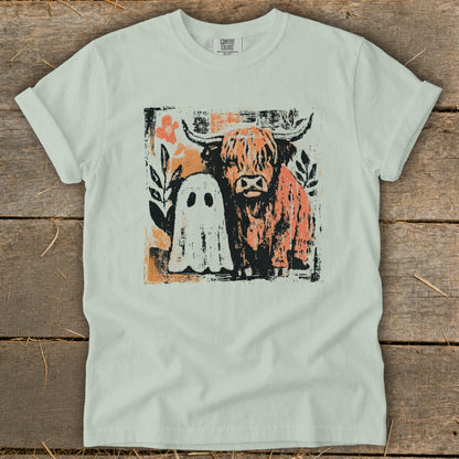 Highland cow and ghost graphic print on a light green t-shirt.