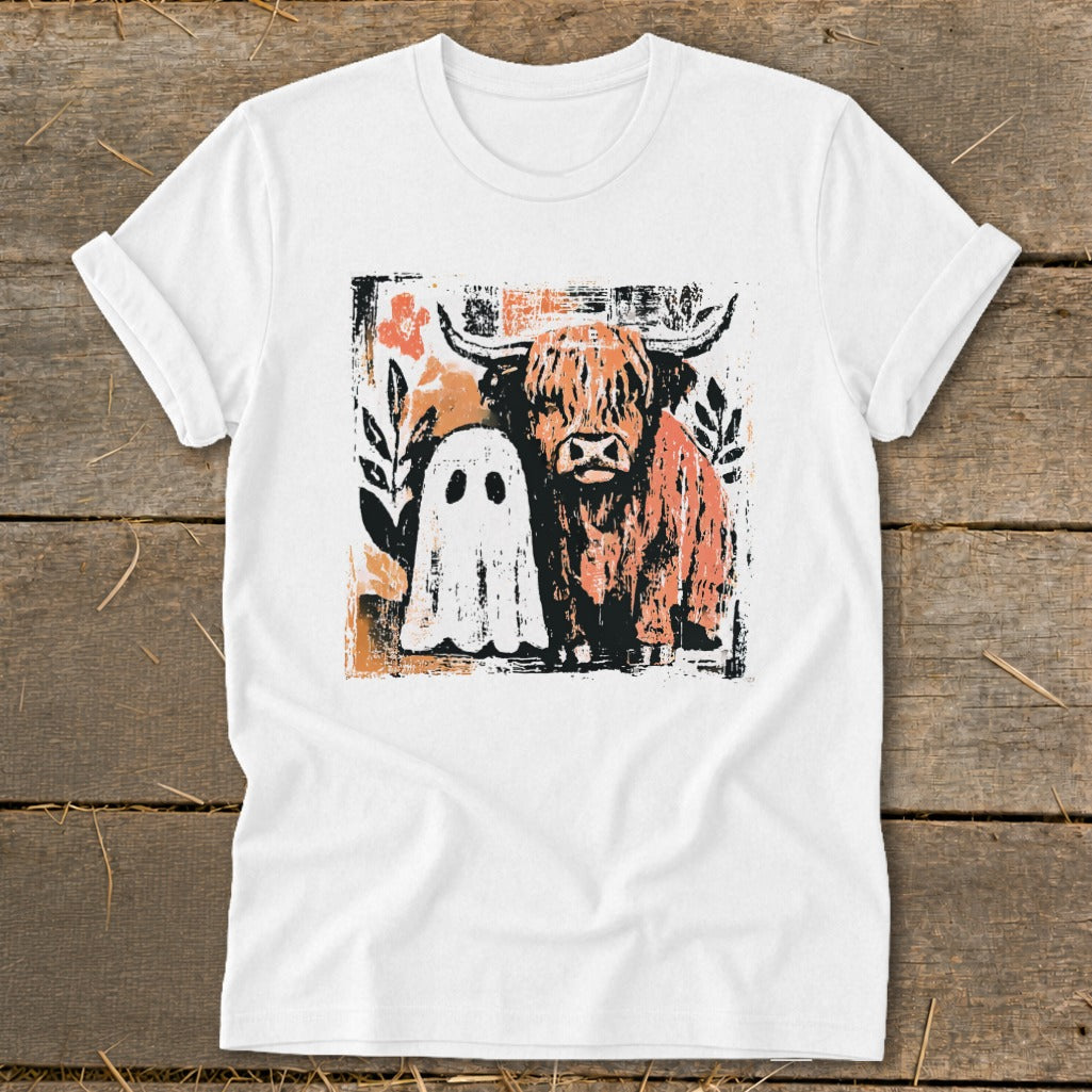 White t-shirt with a graphic of a Highland cow and a ghost amidst floral and abstract elements.