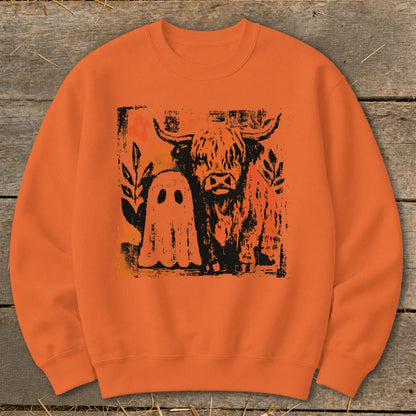 Orange sweatshirt with highland cow and ghost graphic.