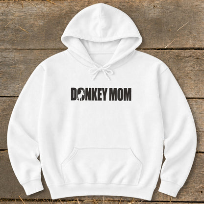 White hooded sweatshirt laid flat on a wooden surface, featuring the black text DONKEY MOM with a silhouette of a donkey replacing the letter O.