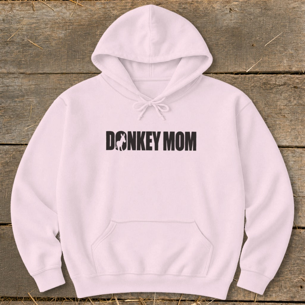 Light pink hooded sweatshirt featuring black text reading DONKEY MOM with a small donkey silhouette inside the letter O, displayed flat on a wooden surface.