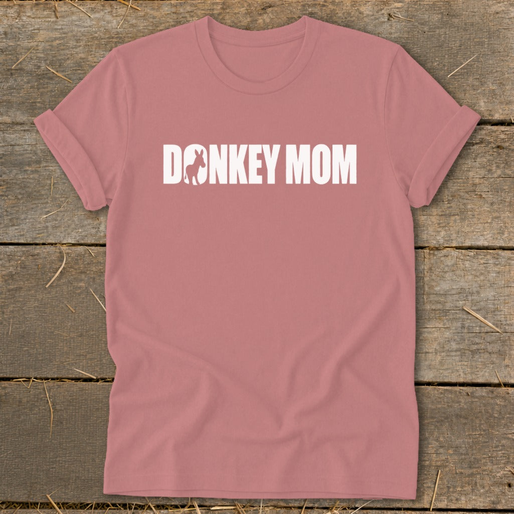 Dusty pink t-shirt with rolled sleeves displaying white text reading DONKEY MOM with a donkey silhouette inside the letter O.