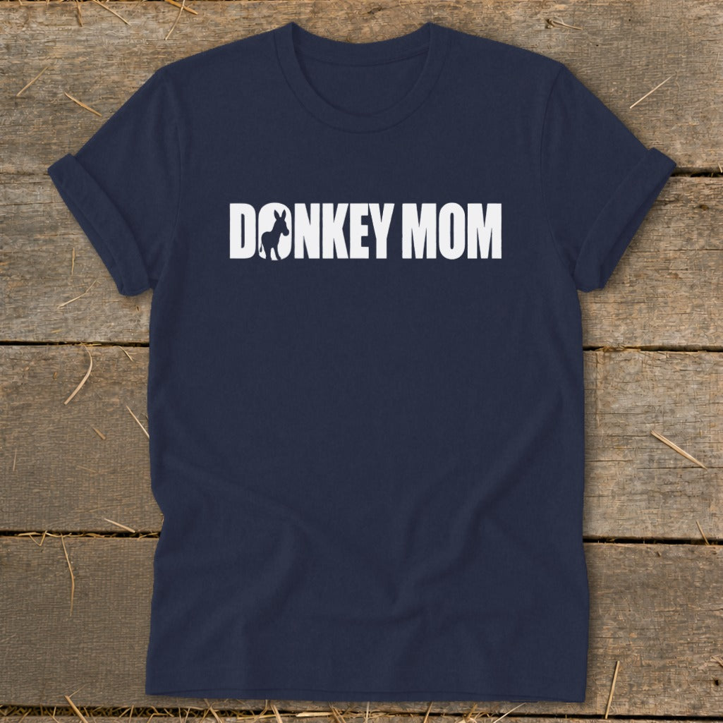 Dark blue short-sleeve t-shirt with white text reading DONKEY MOM on a rustic wooden background.