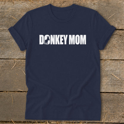Dark blue short-sleeve t-shirt with white text reading DONKEY MOM on a rustic wooden background.