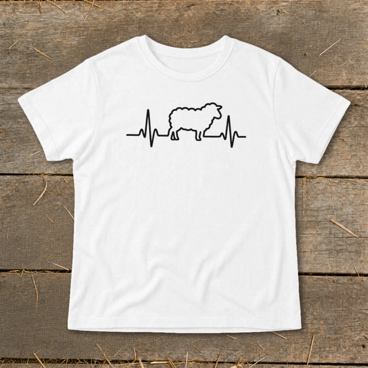 A white crewneck t-shirt featuring a black graphic of a sheep integrated into a heartbeat line, laid flat on a wooden background.