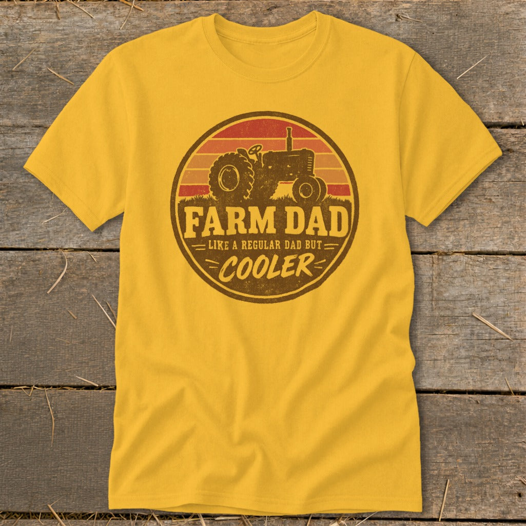 A yellow t-shirt featuring a circular graphic with a tractor, sunset, and text reading FARM DAD LIKE A REGULAR DAD BUT COOLER.