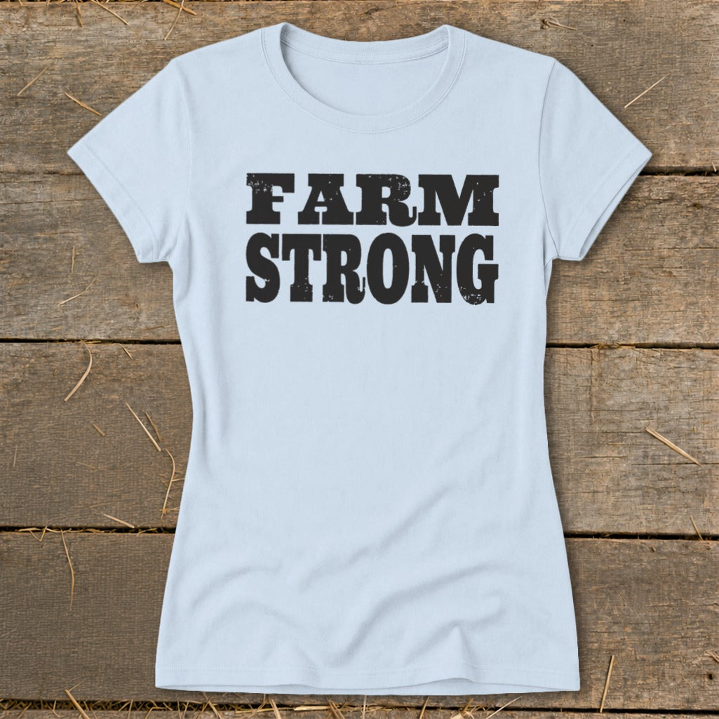 Light blue women's t-shirt featuring the distressed black text FARM STRONG displayed across the chest.