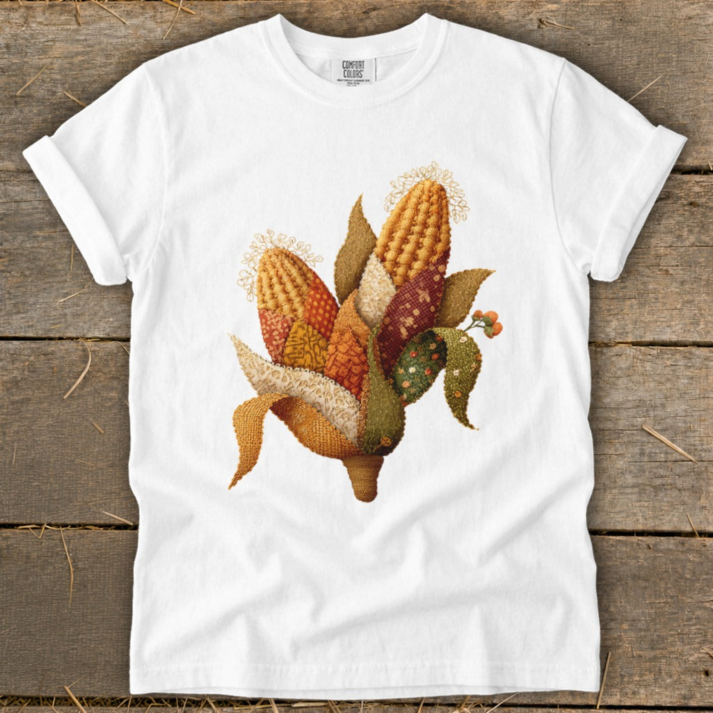 White t-shirt with stitched corn husks and kernels graphic.