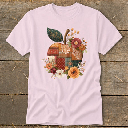 Pink t-shirt with a patchwork apple design featuring flowers and a leaf.