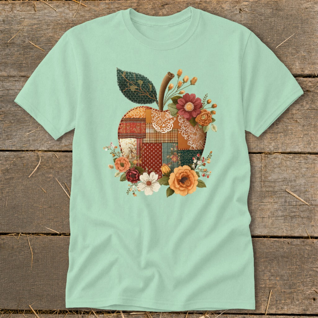 Mint t-shirt with a patchwork apple graphic surrounded by flowers.