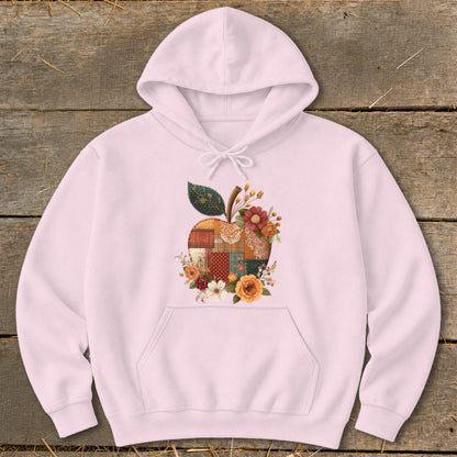 Pink hoodie with a patchwork apple graphic adorned with flowers and leaves.