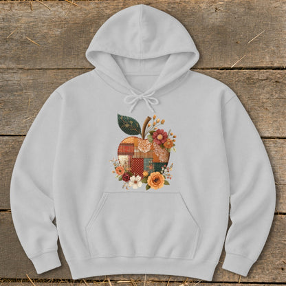 Light grey hoodie with a patchwork apple graphic surrounded by flowers.
