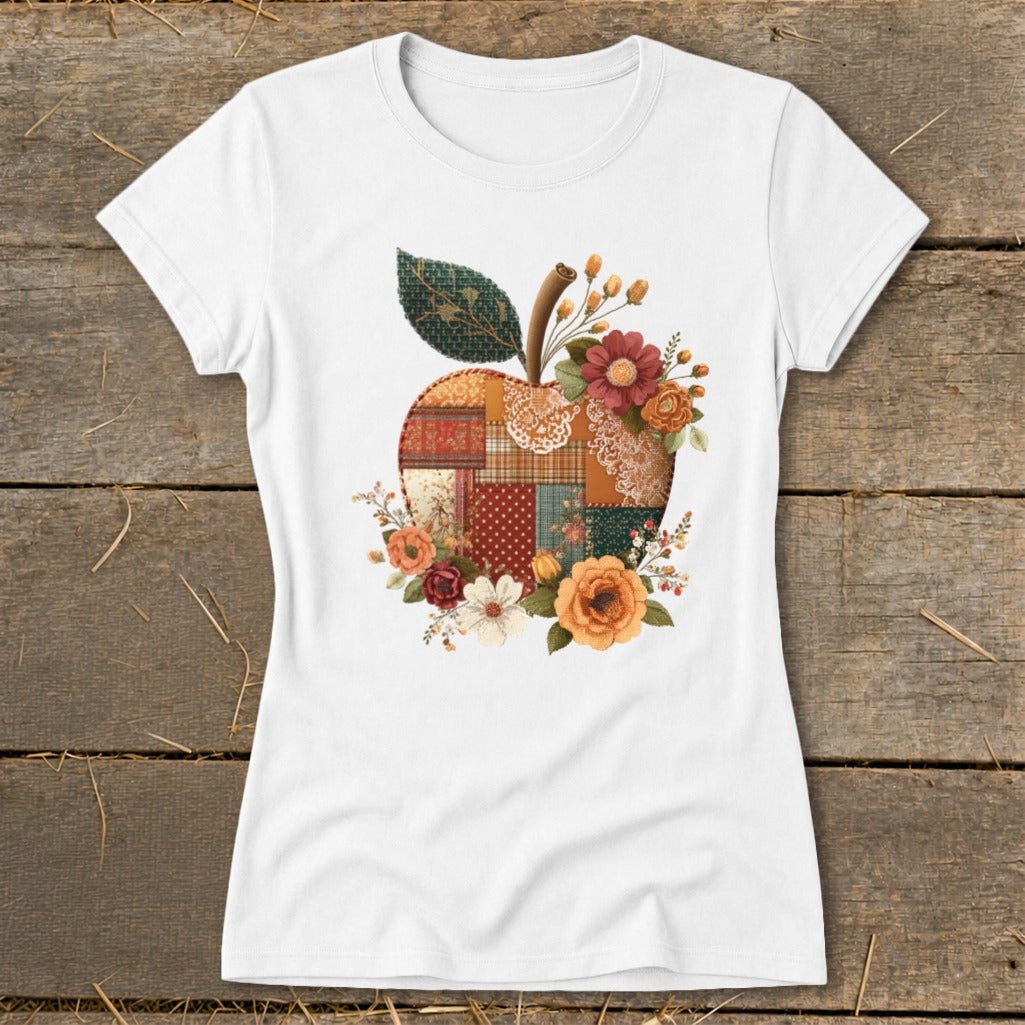 White t-shirt with a patchwork apple graphic and floral accents.