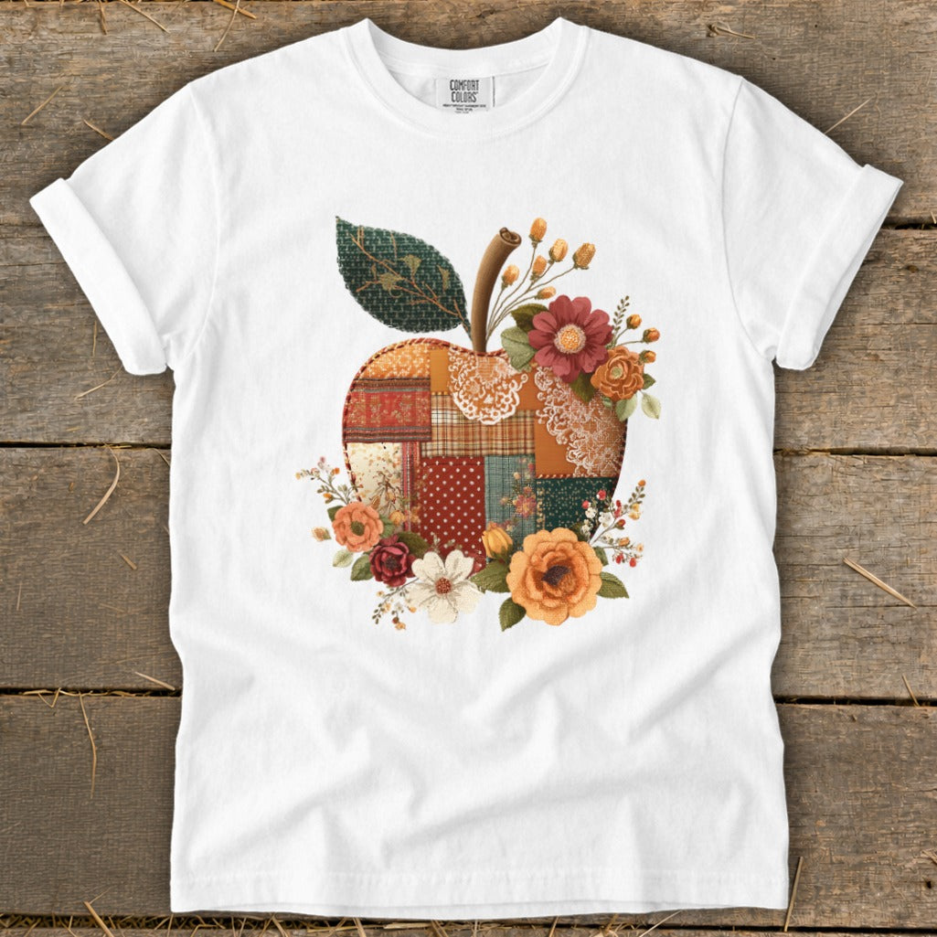 White t-shirt with a patchwork apple design adorned with flowers.