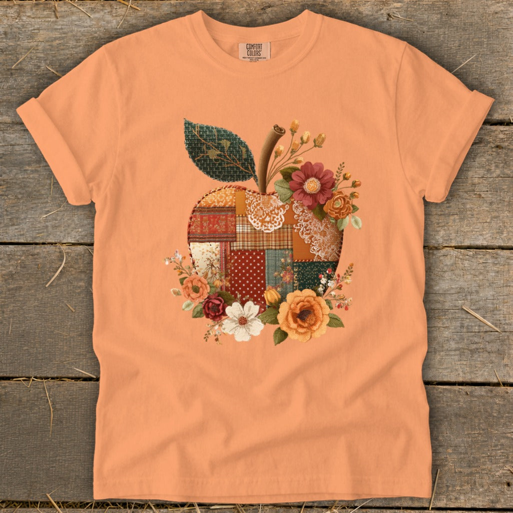 Orange t-shirt with a quilted apple design and floral accents.