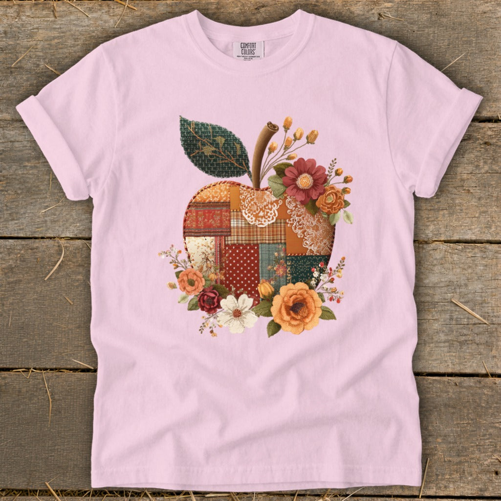 Pink t-shirt with a patchwork apple graphic surrounded by flowers.