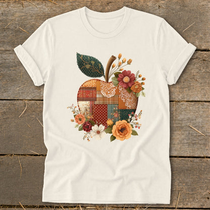 Cream t-shirt with a patchwork apple design and floral accents.