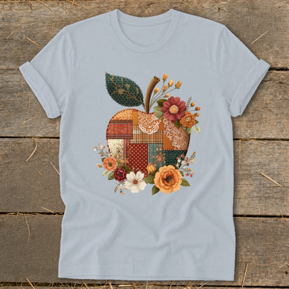 Light blue t-shirt with a patchwork apple design surrounded by flowers.