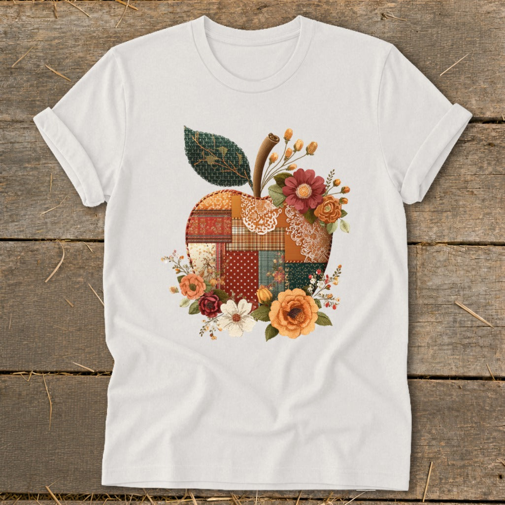 White t-shirt with a quilted apple graphic surrounded by autumn flowers.
