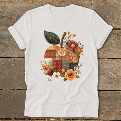 White t-shirt with a quilted apple graphic surrounded by autumn flowers.