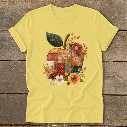 Yellow t-shirt with a patchwork apple graphic adorned with flowers and a leaf.