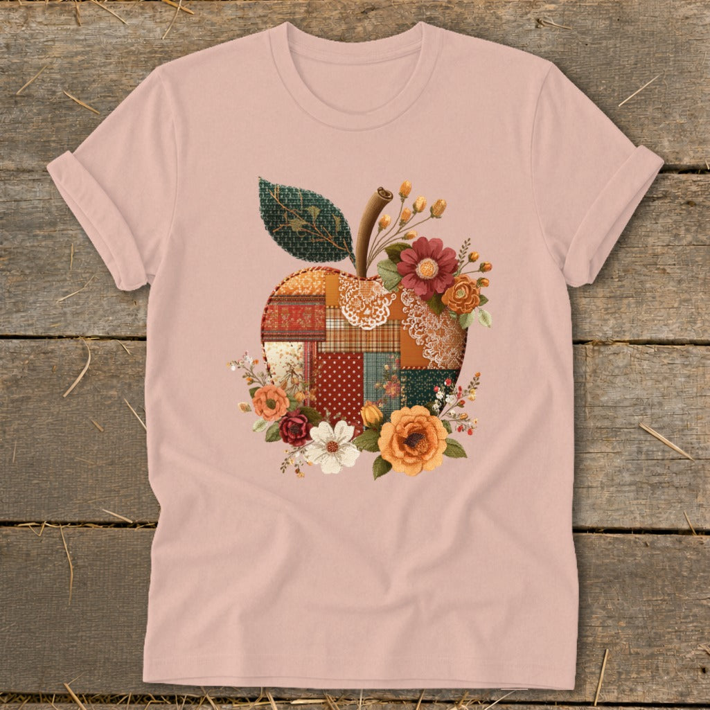 Pink t-shirt with patchwork apple graphic and floral accents.